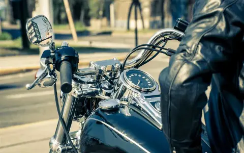 Man in leather jacket on motorcycle, dashboard shows alta temperatura eccessiva liquido radiatore.