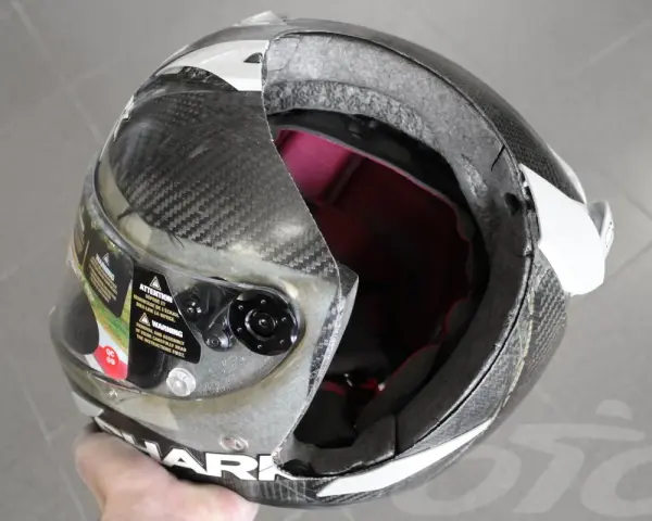 Casco da moto con calotta in fibra di carbonio e abs o policarbonato, visiera trasparente e interni rossi. La calotta presenta una crepa.