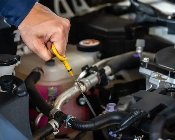 Controllo dei liquidi motore: una mano estrae l'astina per verificare il livello dell'olio.