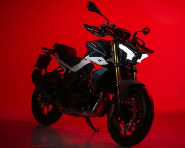 La Benelli TNT 500, con il suo design aggressivo e i fari a LED luminosi, si staglia su uno sfondo rosso acceso, pronta a conquistare la strada.
