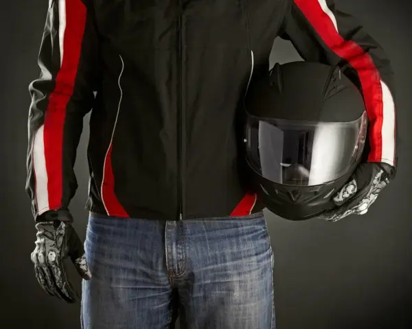 Motociclista con giacca nera e strisce rosse, jeans e casco nero. Le giacche ad uso motociclistico sono pronte per la strada.