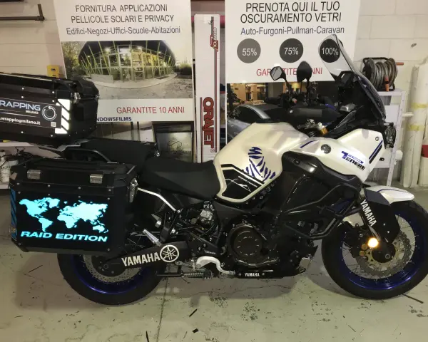 Moto Yamaha Super Ténéré con valigie personalizzate, una con mappa del mondo luminosa e scritta "Raid Edition". Il wrapping con acqua è un'idea per proteggere la moto.