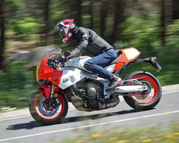 Un motociclista sfreccia su una Yamaha XSR900 GP, con il paesaggio sfocato dallo sfondo verde e giallo.
