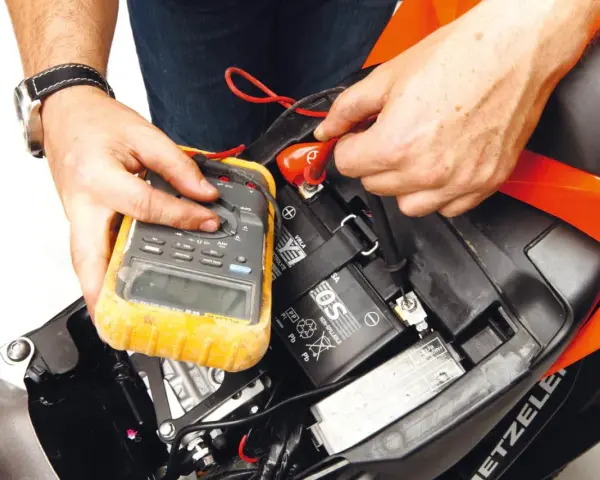 Si accende il quadro ma la moto non parte. Un tecnico controlla la batteria con un multimetro, sperando di risolvere il problema.