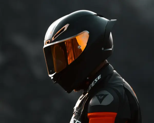 Casco da moto integrale nero con visiera arancione riflettente, pronto per la pista.