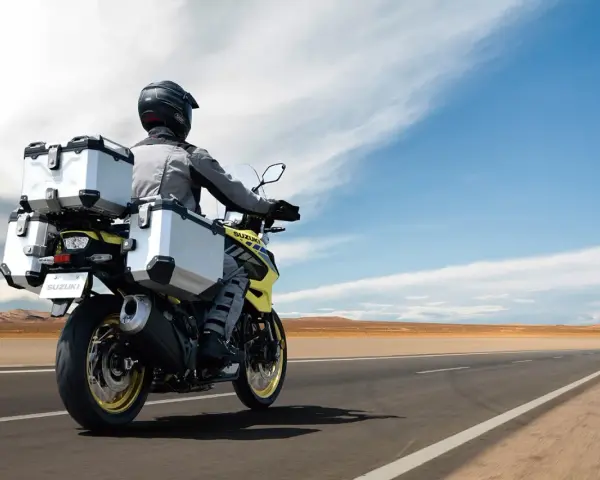 Motociclista con abbigliamento tecnico, ideale per capire come vestirsi in moto d'estate, viaggia su una Suzuki con borse laterali e posteriori.