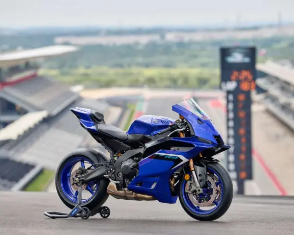 Yamaha R9, blu, su un cavalletto, con sfondo di un circuito. Dettagli tecnici da scoprire.