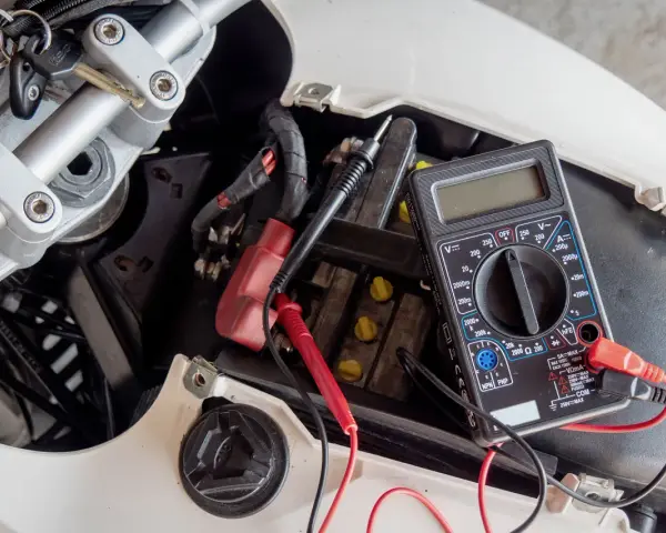 Multimetro collegato alla batteria di uno scooter per verificarne lo stato, un passo fondamentale per capire come caricare batteria scooter.