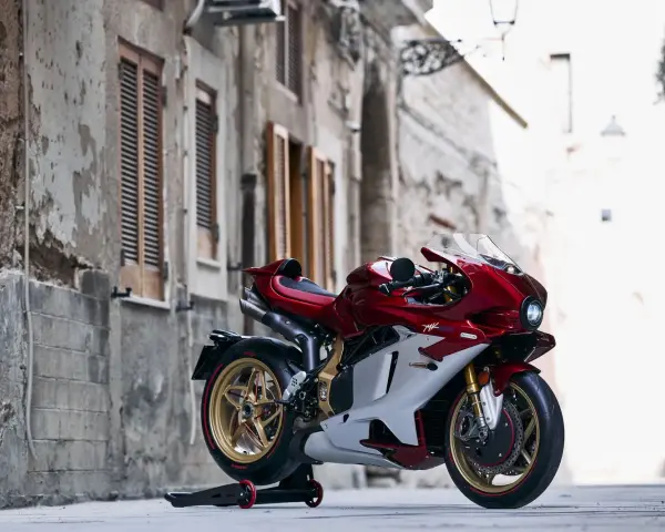 MV Agusta rossa e bianca, la più costosa, su un cavalletto in un vicolo storico.