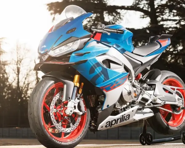 Aprilia carenata blu e rossa, con cerchi rossi, pronta per sfrecciare su pista.