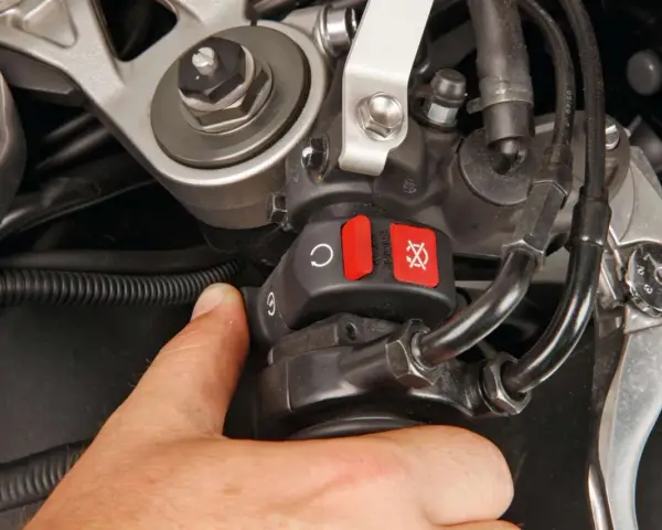 Il motorino gira ma la moto non parte. Il pollice preme il pulsante di accensione, ma il motore resta muto.