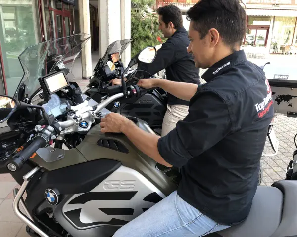 Due uomini in moto BMW, forse in fase di rodaggio, con abbigliamento tecnico. Il significato del rodaggio è fondamentale per la longevità del mezzo.