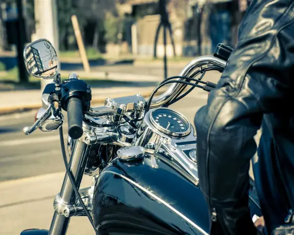 Man in leather jacket on motorcycle, dashboard shows alta temperatura eccessiva liquido radiatore.