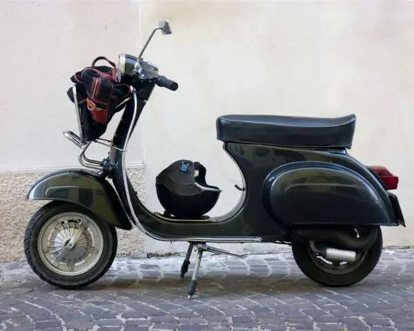 Moto d'epoca, un classico intramontabile. Dopo quanti anni mantiene ancora il suo fascino? Un casco e una borsa completano il look.