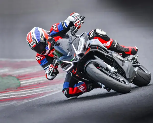 Un pilota in piega su una Aprilia Tuono 660 Factory, con tuta rossa e blu, affronta una curva su pista.