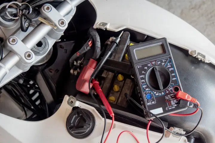 Multimetro collegato alla batteria di uno scooter per verificarne lo stato, un passo fondamentale per capire come caricare batteria scooter.