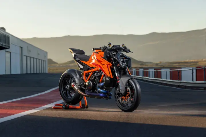 KTM 1290 Duke arancione su un cavalletto, pronta per sfrecciare su un circuito al tramonto.