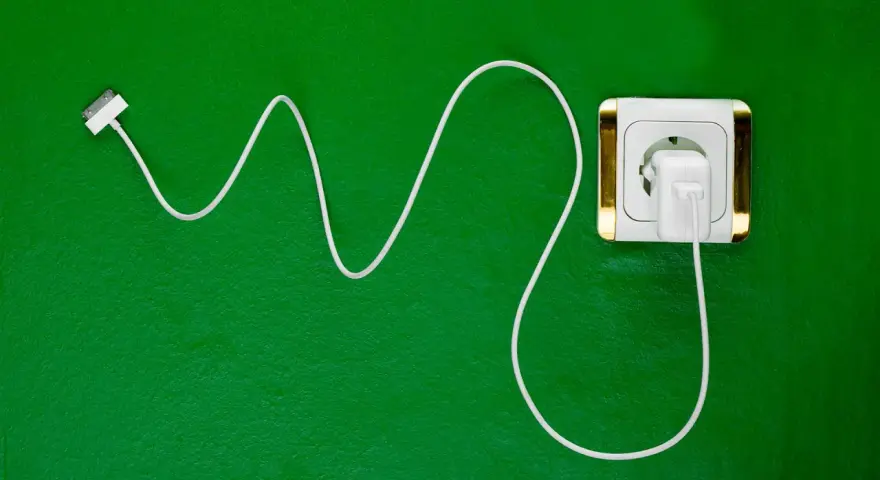 Cavo bianco collegato a una presa elettrica dorata. Si può lasciare il caricabatterie attaccato per avere sempre energia.