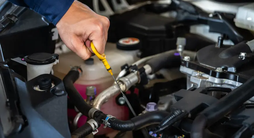 Controllo dei liquidi motore: una mano estrae l'astina per verificare il livello dell'olio.