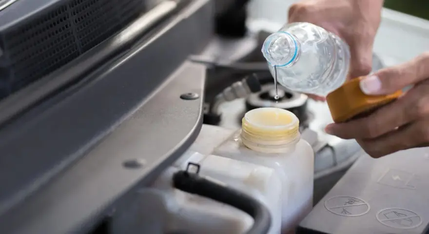 Mani versano acqua nel serbatoio del liquido di raffreddamento dell'auto, assicurandosi che ci sia acqua nel radiatore.
