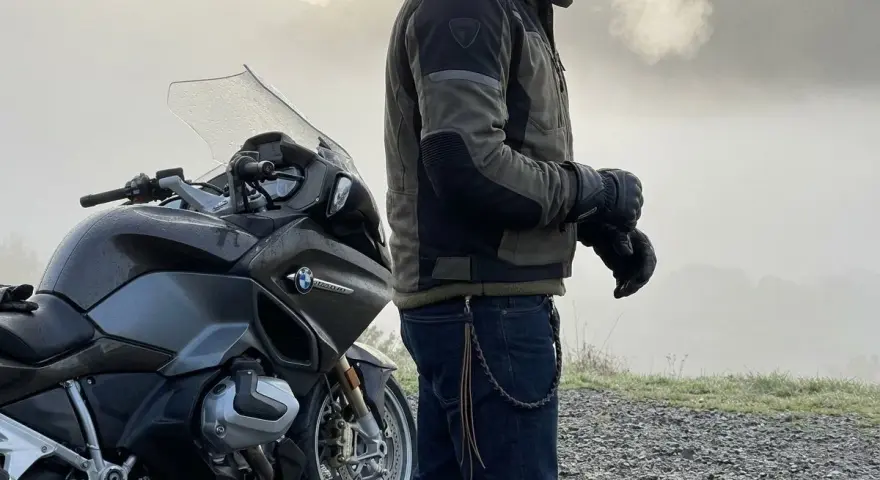 Motociclista con giacca tecnica e jeans, pronto per un'avventura. Ecco come vestirsi per andare in moto in ogni condizione.