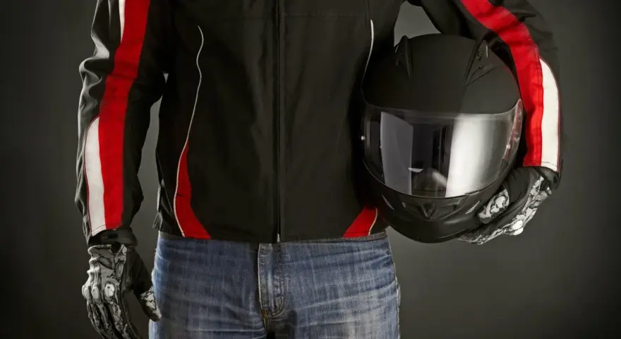 Motociclista con giacca nera e strisce rosse, jeans e casco nero. Le giacche ad uso motociclistico sono pronte per la strada.