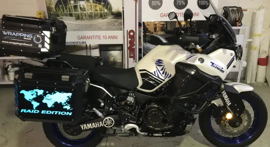Moto Yamaha Super Ténéré con valigie personalizzate, una con mappa del mondo luminosa e scritta "Raid Edition". Il wrapping con acqua è un'idea per proteggere la moto.
