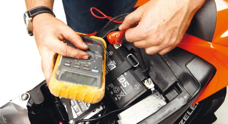 Si accende il quadro ma la moto non parte. Un tecnico controlla la batteria con un multimetro, sperando di risolvere il problema.