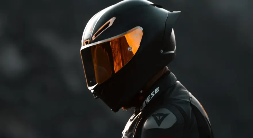 Casco da moto integrale nero con visiera arancione riflettente, pronto per la pista.