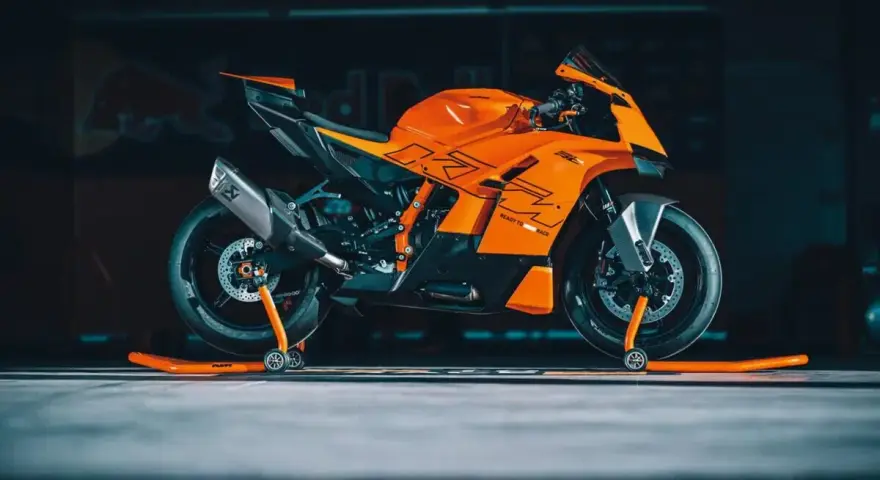 La KTM 890 Duke GP, arancione e nera, pronta per la pista, con scarico Akrapovič e cavalletti arancioni.