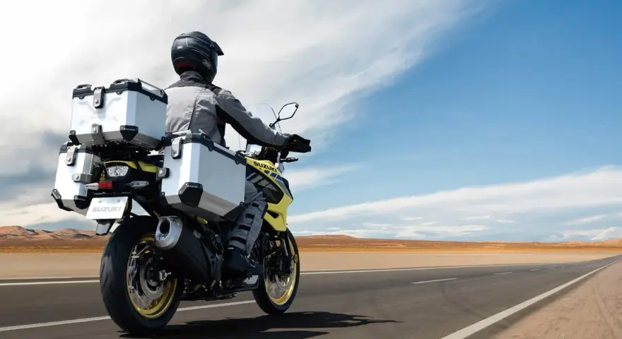 Motociclista con abbigliamento tecnico, ideale per capire come vestirsi in moto d'estate, viaggia su una Suzuki con borse laterali e posteriori.