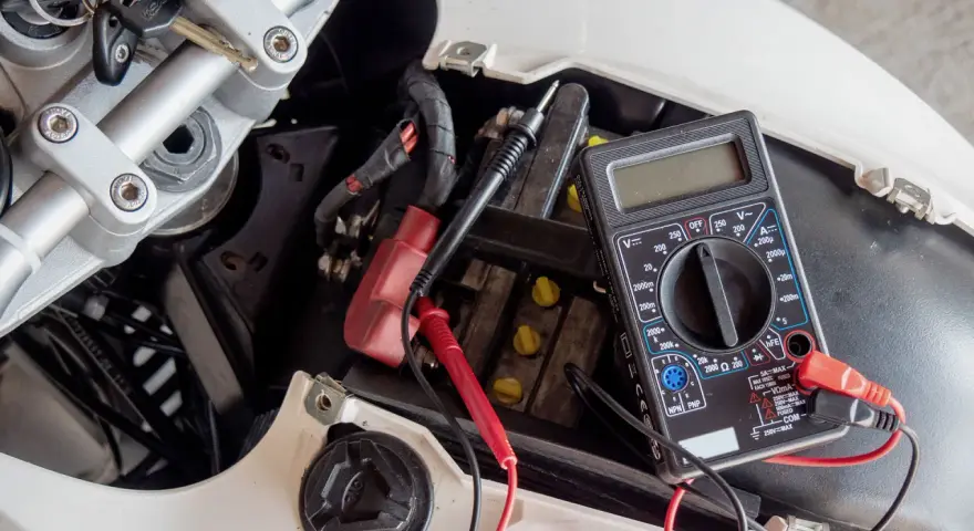 Multimetro collegato alla batteria di uno scooter per verificarne lo stato, un passo fondamentale per capire come caricare batteria scooter.
