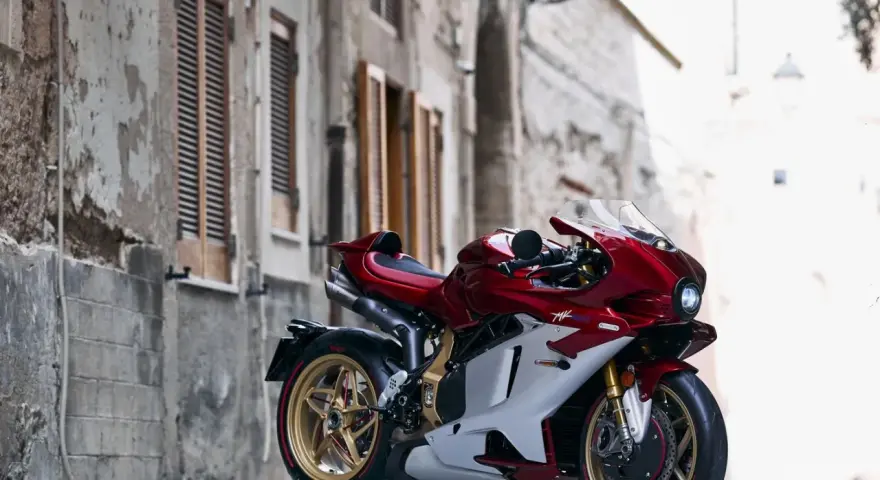 MV Agusta rossa e bianca, la più costosa, su un cavalletto in un vicolo storico.