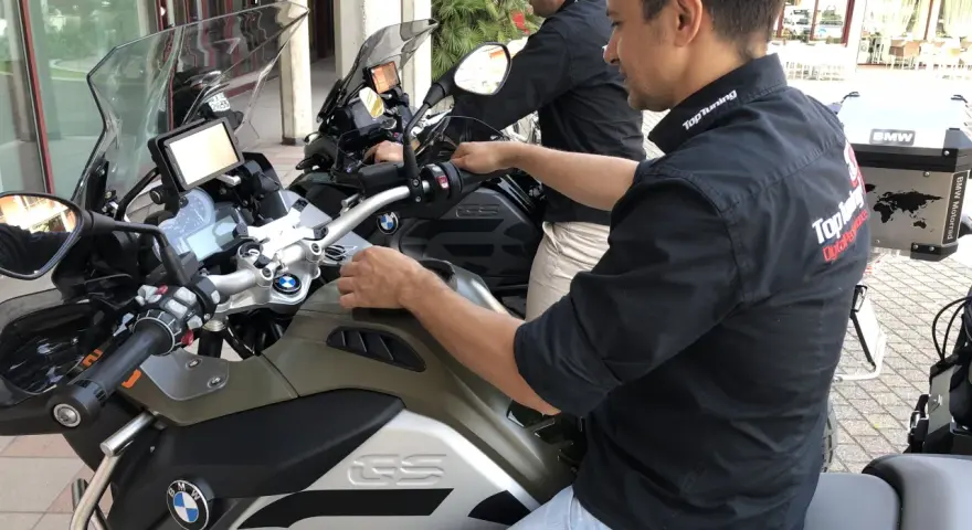 Due uomini in moto BMW, forse in fase di rodaggio, con abbigliamento tecnico. Il significato del rodaggio è fondamentale per la longevità del mezzo.