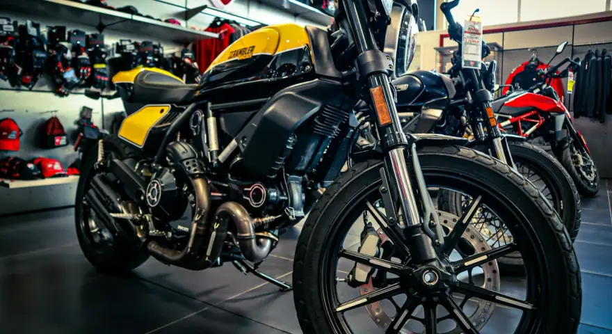 Una moto gialla e nera, con altre moto in esposizione. Diversi tipi di moto pronti per essere scelti.