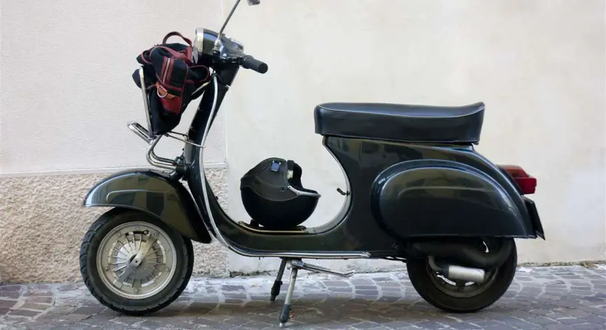 Moto d'epoca, un classico intramontabile. Dopo quanti anni mantiene ancora il suo fascino? Un casco e una borsa completano il look.