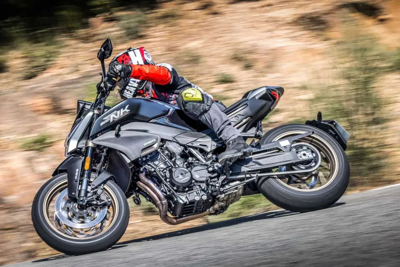 Un motociclista in piega su una CFMOTO 800 NK, con il motore a vista e lo sfondo sfocato che suggerisce velocità.