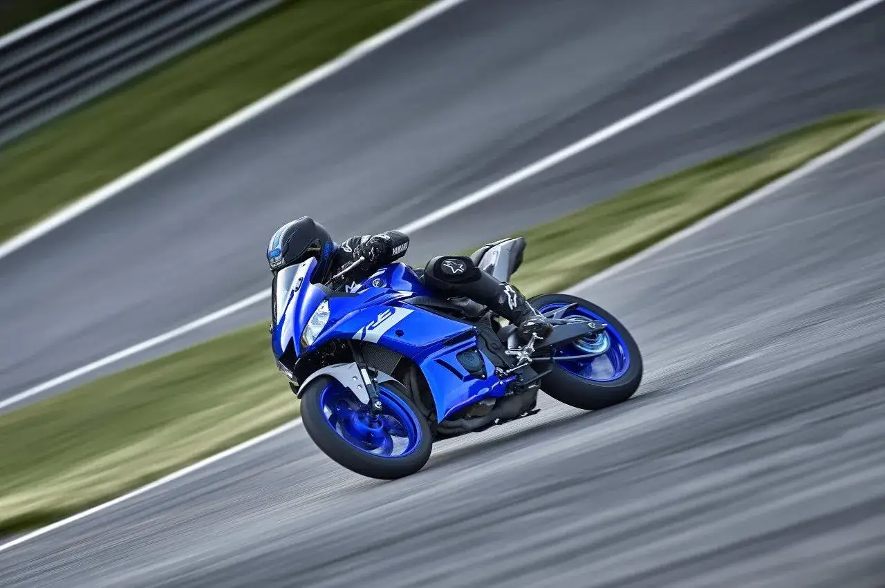 Motociclista in piega su una Yamaha R3 blu su pista. Il suo peso è ben bilanciato, agile e veloce.