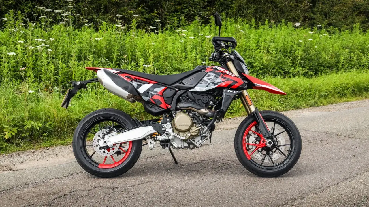 Ducati Hypermotard 698 Mono, una delle moto leggere 600 più agili, parcheggiata su strada con sfondo verde.