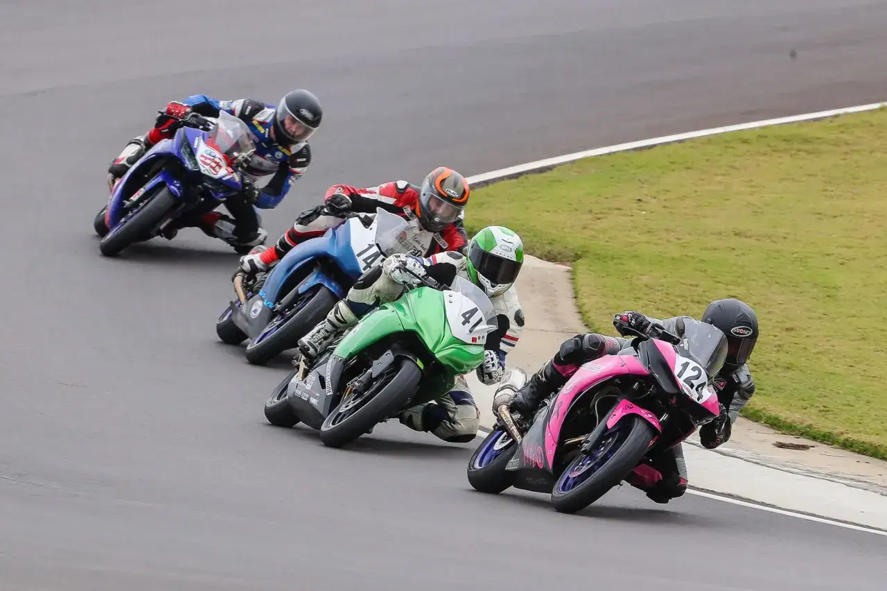 Piloti in gara con le migliori moto sportive, piegati in curva su un circuito.