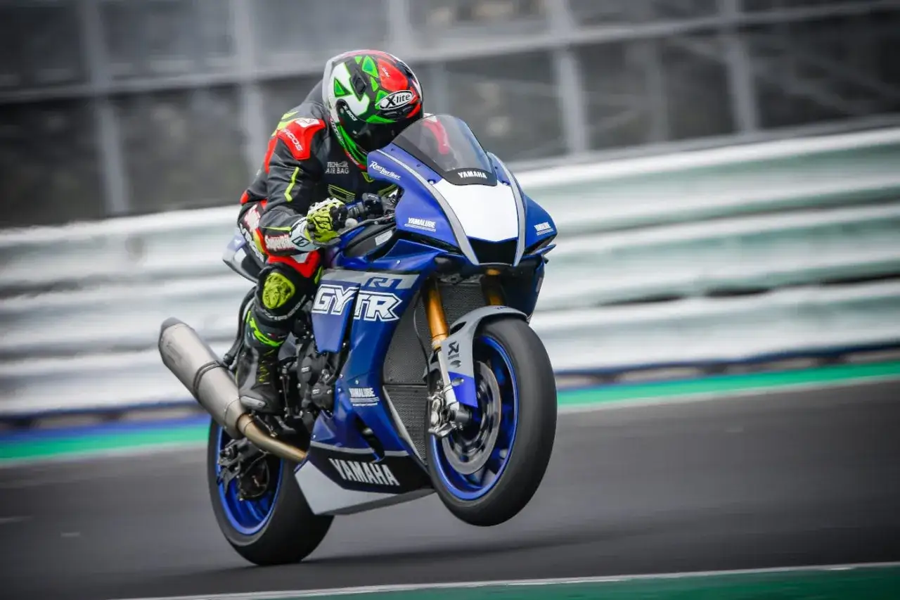 Un pilota su una Yamaha R1 SBK in pista, con la ruota anteriore sollevata.