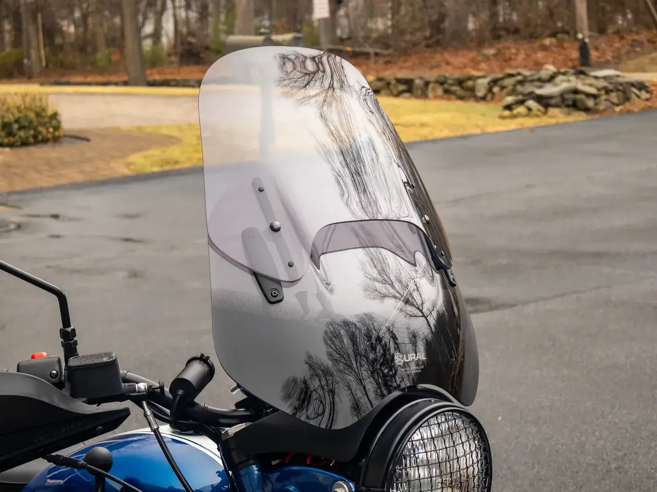 Manubrio e parabrezza di una moto, perfetta per la moto per città e viaggi. Riflessi di alberi sul parabrezza.
