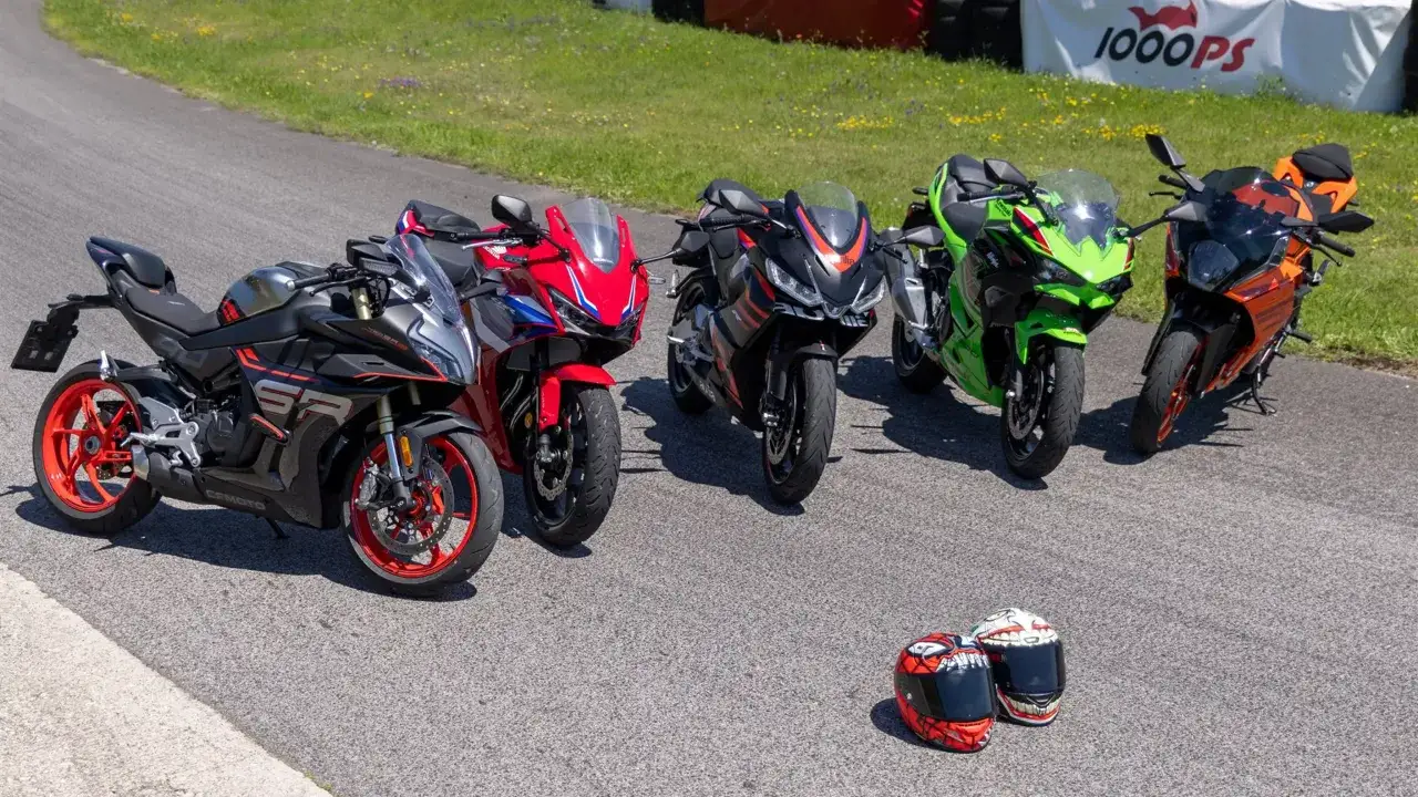 Cinque moto sportive, tra cui una CF Moto e una KTM, pronte per la pista. Due caschi decorati a terra.