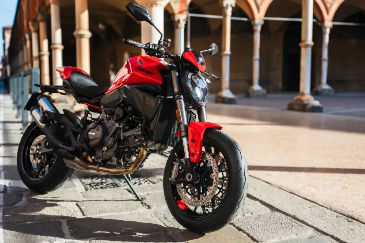 La nuova Monster rossa Ducati, con il suo design aggressivo, è parcheggiata su un selciato antico, sotto un portico suggestivo.