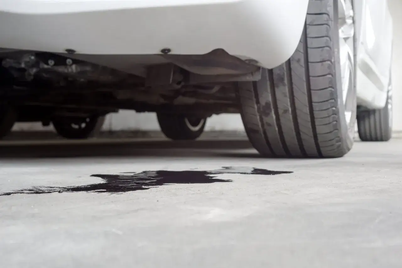 Macchia scura sotto un'auto, possibile perdita dal radiatore senza acqua.