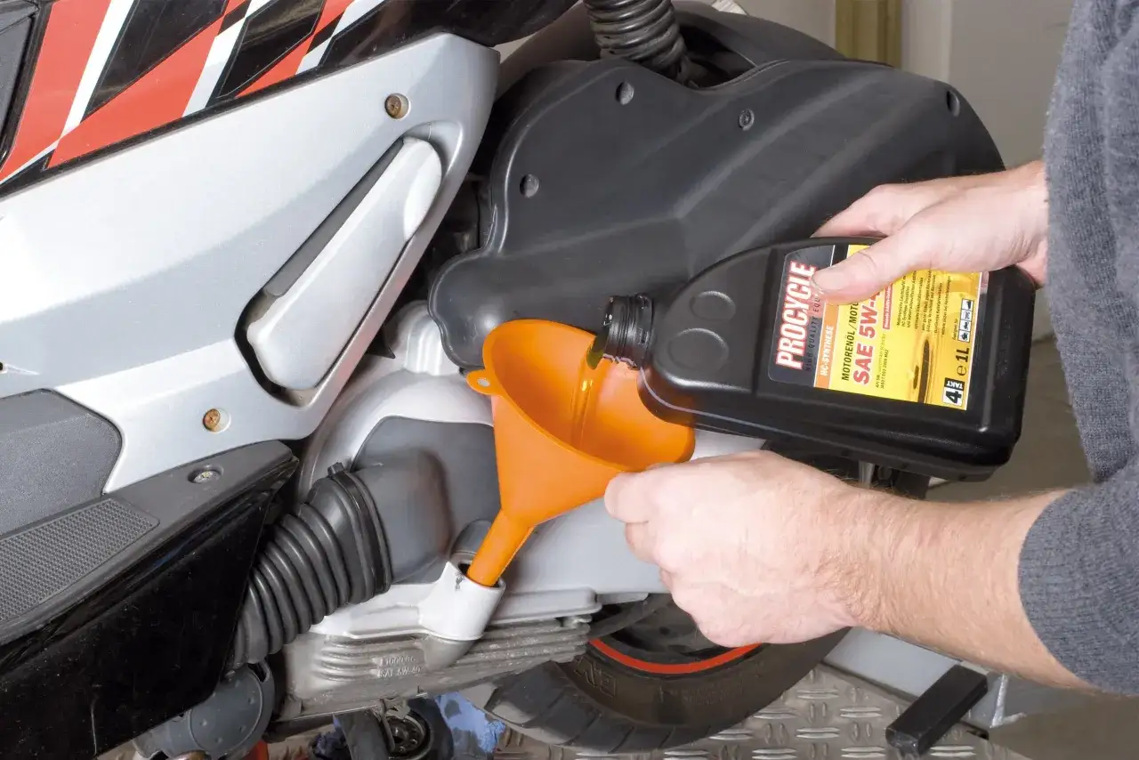 Man versa olio motore in uno scooter 125. La manutenzione &egrave; fondamentale per sapere quanti km pu&ograve; fare uno scooter 125.
